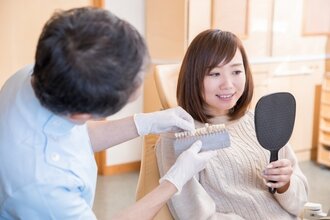 鏡を見ながら歯の色を確認している歯科医師と女性